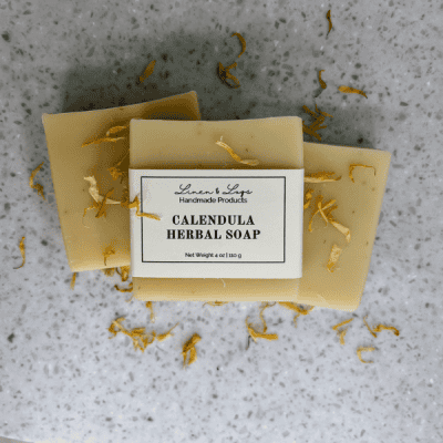 Calendula Herbal Tallow Soap bars laying in a pile with dried calendula flower petals around the soap