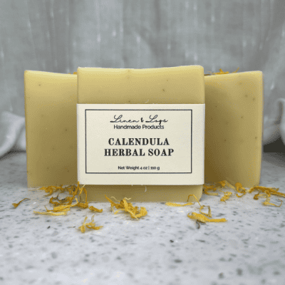 3 bars of Calendula Herbal Tallow Soap standing on end with a sprinkle of dried calendula flowers in front