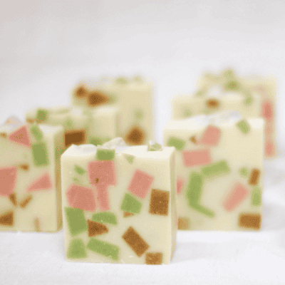 bars of citrus tallow soap standing up - speckled with pink, green, and turmeric chunks.