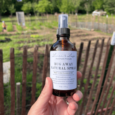 hand holding an amber glass bottle of bug away all-natural spray (made with essential oils)