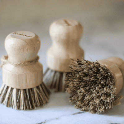 three pot scrubber brushes - two standing on bristles, one brush laying on side showing bristles