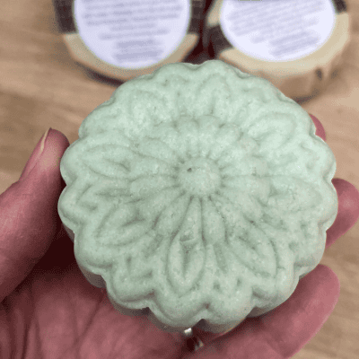 hand holding a flower shaped shampoo bar