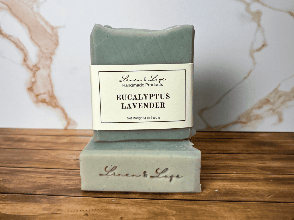 a bar of eucalyptus lavender soap sitting on top of another bar of soap. Shows the label and Linen & Logs soap stamp on bars of soap